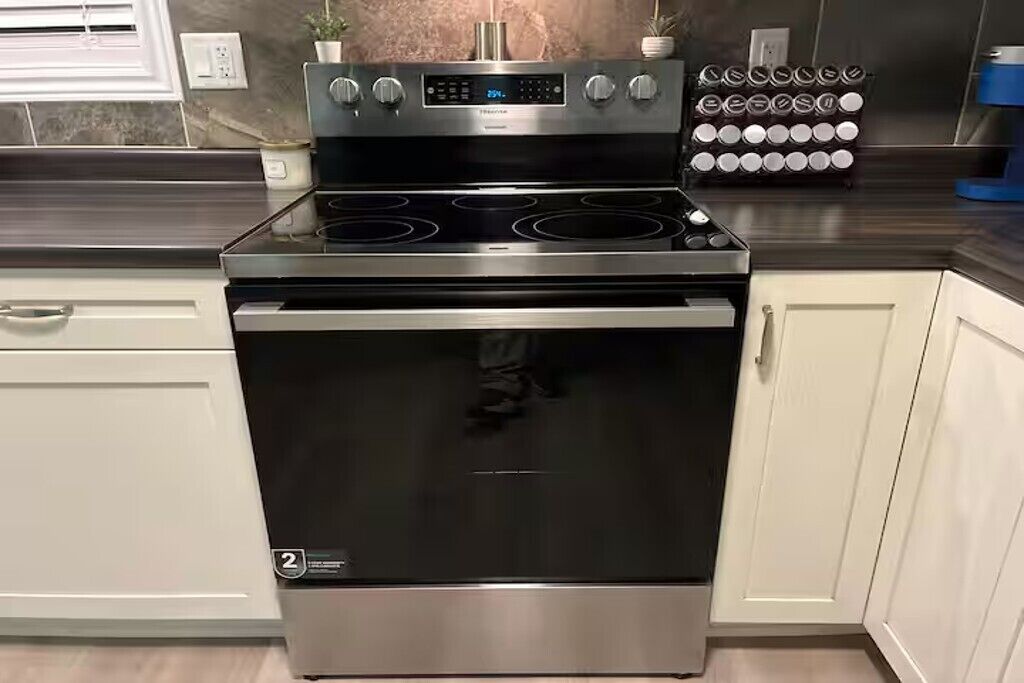 Une cuisinière en acier inoxydable dotée de quatre brûleurs, d’un panneau de commande numérique et d’une porte de four en acier inoxydable.