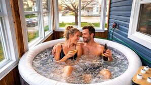 A couple in a hot tub with a view of a house and street outside. - Hot Tub Retreat Near Downtown & Casino | Sleeps 8 | Cozy Luxury Stay for family✨ (Windsor)