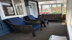 A covered porch with wicker furniture and a bench, a covered window, and a view of a street. - Hot Tub Retreat Near Downtown & Casino | Sleeps 8 | Cozy Luxury Stay for family✨ (Windsor)