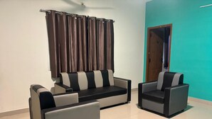 A modern living room with a sofa and two armchairs, a curtain, and a teal wall. - Thamira Residency (Yercaud)