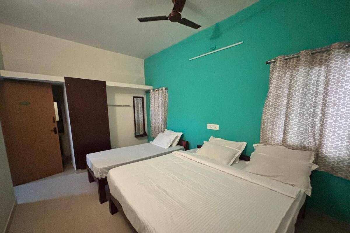 Una habitación con dos camas, un ventilador de techo, una puerta y una ventana con cortinas.