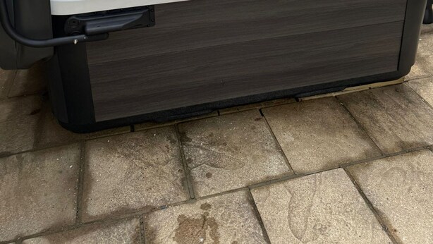 A hot tub with a wooden deck and a brick wall in the background. - The Ivies - 5 Bedroom Property - Tenby (Tenby)