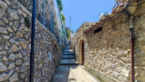 Um beco de pedra estreito com uma escadaria que sobe.