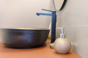 Ein Waschtisch mit modernem Wasserhahn, einer Schüssel und einer strukturierten Seifenspender.