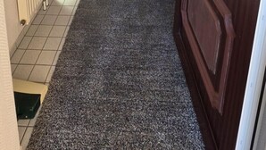 Un pasillo que conduce a un comedor con una mesa, sillas, un radiador y una puerta de paneles de vidrio.