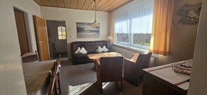 Ett rum med en säng, en soffa, ett matbord och ett fönster med gardiner.
