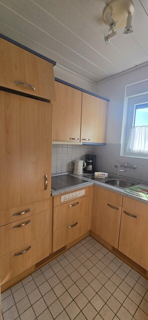 Una cocina con armarios de madera, una encimera, una cafetera y un ventanal con cortinas.