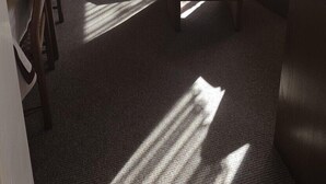 A room with a wooden ceiling, a sofa with cushions, a table, a lamp, and a window with curtains. - Vacation apartment 4 "Borkum" (Borkum)