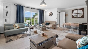 Een moderne woonkamer met een bank, salontafel en eethoek.