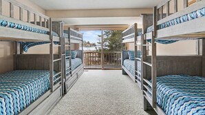 A room with bunk beds, a balcony, and a view of the outdoors. - Waterfront Home Lake Charlevoix Oyster Bay Mooring Buoy Private Dock Beach fire! (Charlevoix)