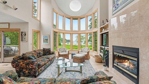 A spacious living room with a large sofa, two armchairs, a glass coffee table, and a fireplace. - Waterfront Home Lake Charlevoix Oyster Bay Mooring Buoy Private Dock Beach fire! (Charlevoix)