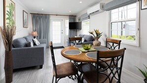 Een moderne woonkamer met een bank, eettafel, stoelen en een televisie.