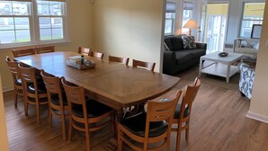 Un amplio salón con una gran mesa de comedor de madera rodeada de sillas, un sofá y una mesita de centro.