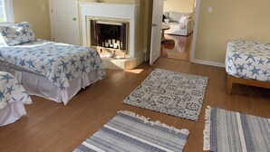 Un dormitorio con dos camas, una chimenea y vistas a una escalera que lleva a otra habitación.