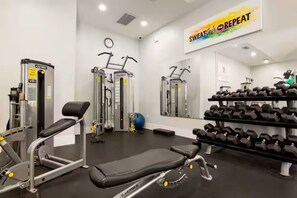 A gym with exercise equipment, dumbbells, and a motivational poster. - Amazing 2-bedroom apartment with AC in vibrant Miami (Miami)