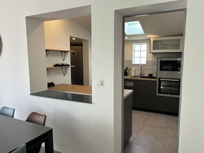 Eine moderne Küche mit integrierten Geräten, ein Essbereich mit Tisch und Stühlen sowie ein Fenster.