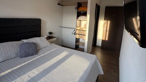 A bedroom with a bed, a bedside table, a nightstand, a built-in wardrobe, and a staircase leading to an upper level. - Nova Stays : Modern in strategic location (Ciudad de Guatemala)