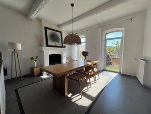 A modern kitchen with a central island, a fireplace, and a dining area with a view to the outside. - Charming village house with garden (Rognes)