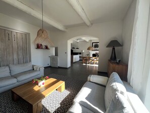 A modern living room with a sofa, coffee table, and a dining area with chairs. - Charming village house with garden (Rognes)