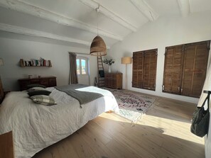 A bedroom with a bed, wooden shutters, a ladder, a lamp, and a bookshelf. - Charming village house with garden (Rognes)