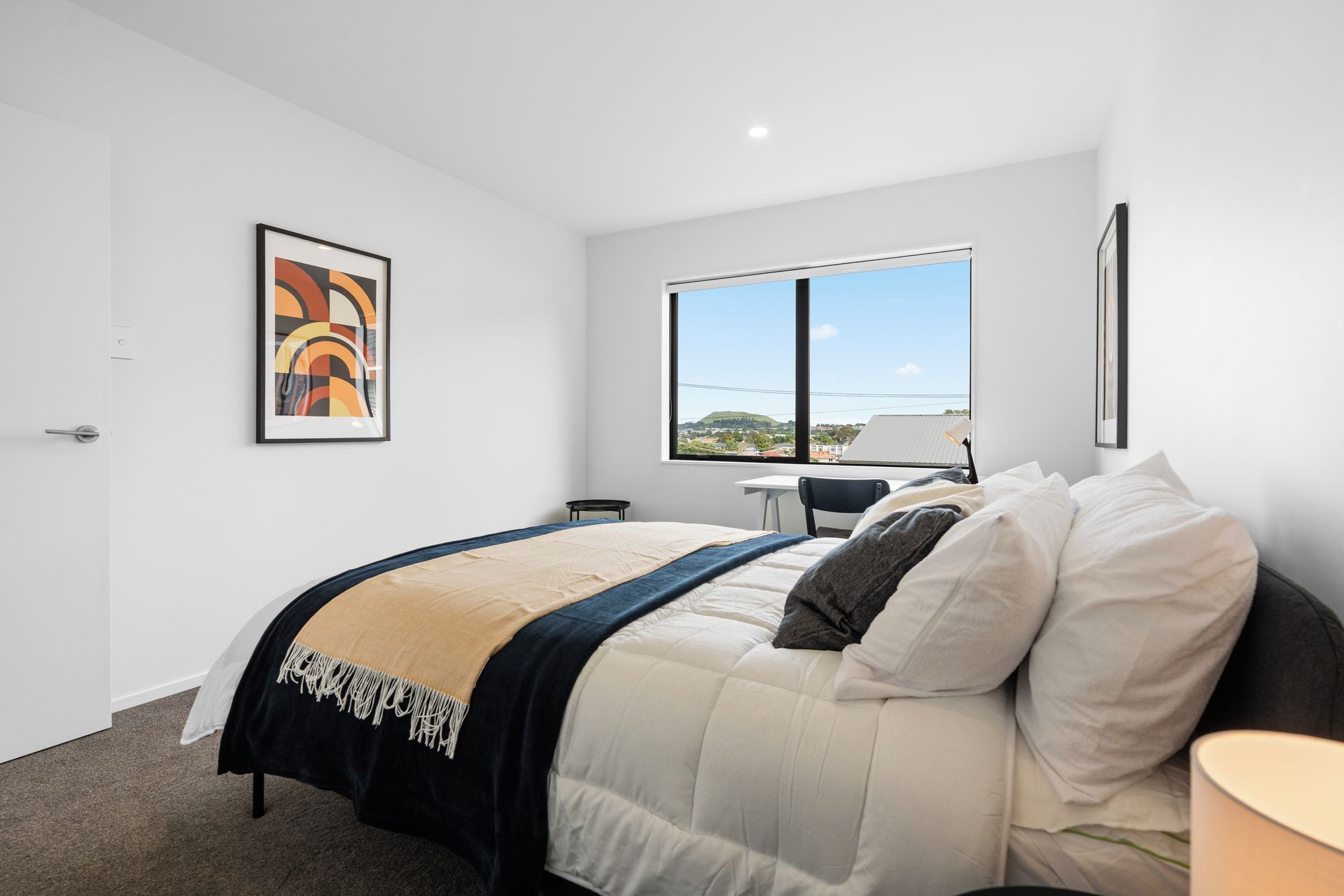 Une chambre moderne avec un lit, un bureau et une fenêtre donnant sur un beau paysage.