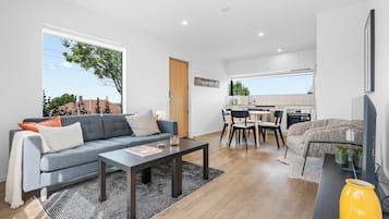 A modern apartment with a living room, dining area, and kitchen.