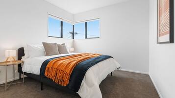 A bedroom with a bed, nightstand, lamp, and a large window.