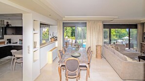 Een moderne keuken met een eetgedeelte, een groot raam, en een woonkamer met een bank en een salontafel.