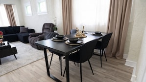 A dining area with a table set for four, surrounded by chairs, in a modern living room with a sofa and a coffee table. - Modern Duplex Near Airport & Downtown + Game Room & Lake (Milwaukee)