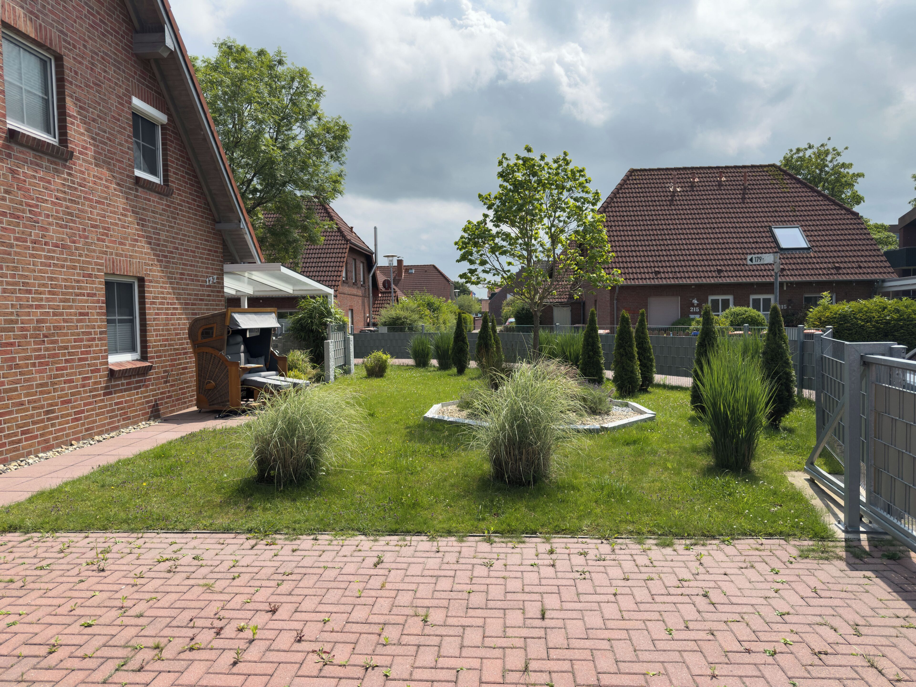A residential area with brick houses, a paved driveway, and a well-maintained lawn.