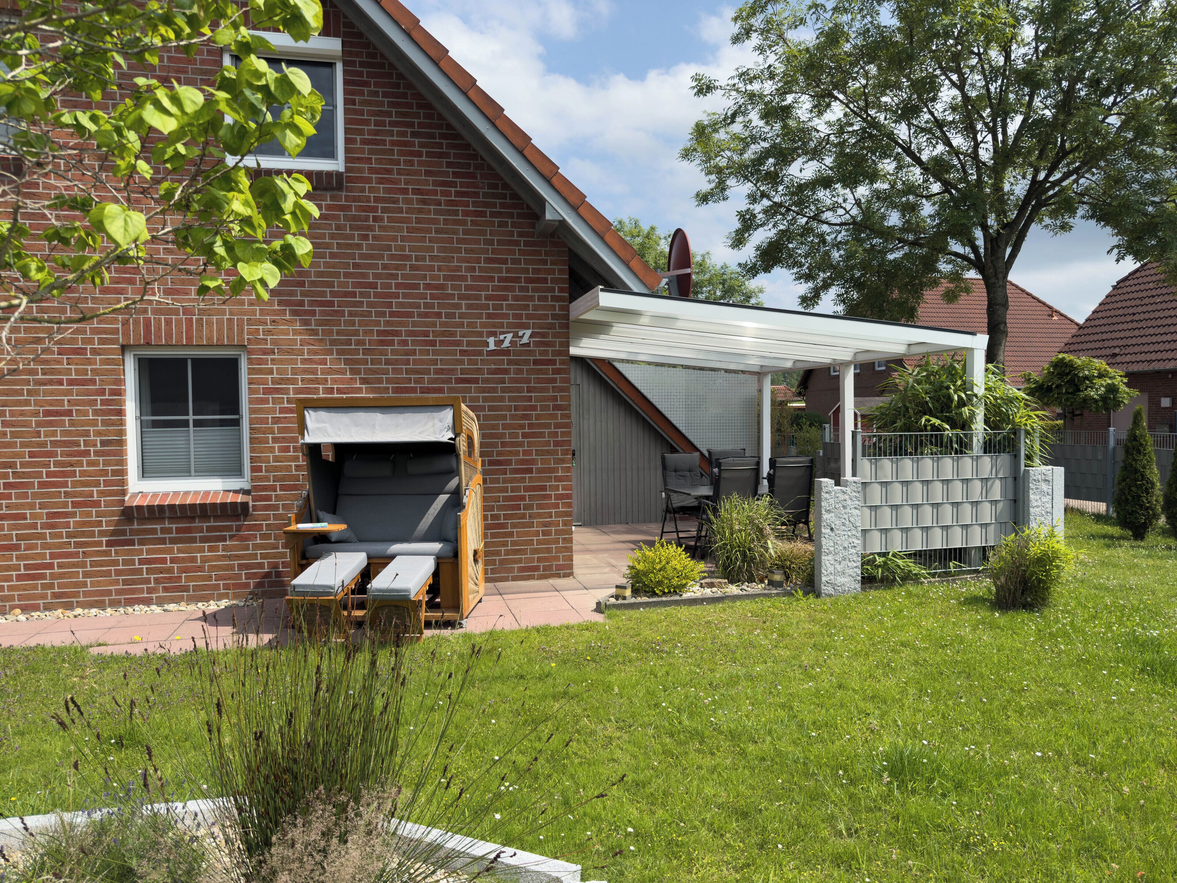 A brick house with a patio, a covered outdoor seating area, and a small garden.