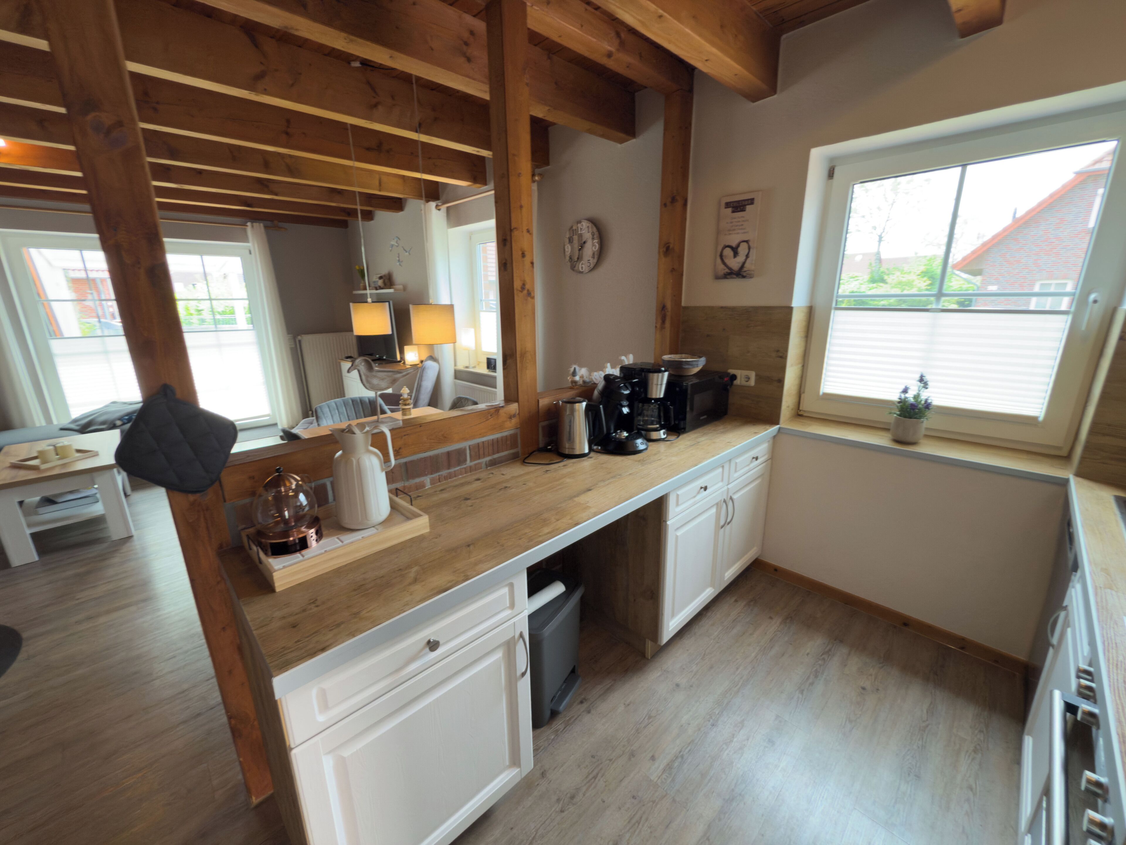 Cocina con vigas de madera, cafetera, hervidor y ventana con vistas.