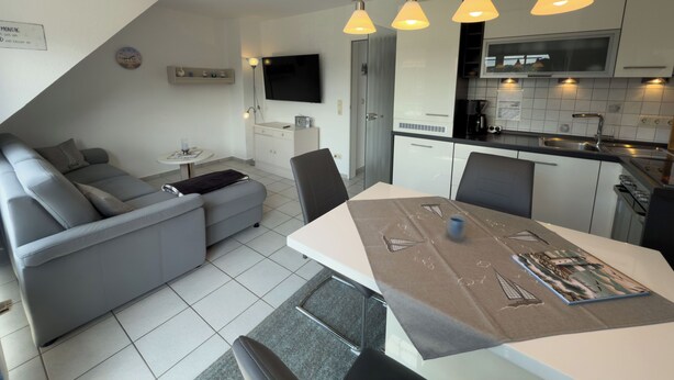 A modern kitchen with white cabinets, a built-in microwave, and a black countertop. - Pelikan vacation apartment (Hooksiel)