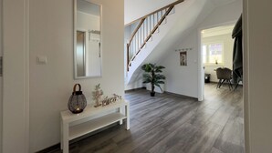 Un intérieur moderne avec un banc blanc, un miroir, un escalier et un coin repas.