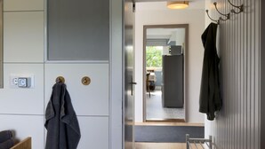 Et moderne køkken med hvide skabe, en indbygget ovn og et væghængt knagered.