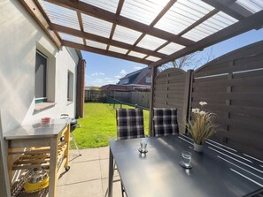 Eine Terrasse mit Tisch, Stühlen und Grill.