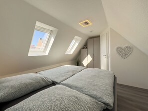 Ein Schlafzimmer mit Bett, Oberlichtern, einem Kleiderschrank und einer Wanddekoration in Herzform.