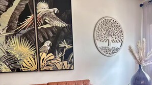 Un salon avec un canapé en cuir marron, une table basse en verre et deux œuvres d’art murales.