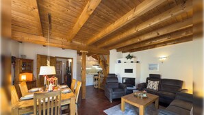 Een houten interieur met een eethoek, een bank en een open haard.