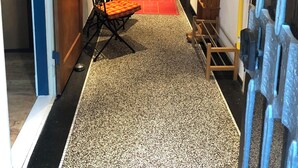 A hallway with a dining area, a wooden door, and a red carpet.