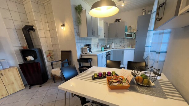 A modern kitchen with white cabinets, a microwave, and a dining area with a table set for two.