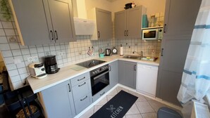 A modern kitchen with grey cabinets, a built-in oven, a sink, and a microwave.