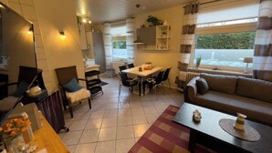 A compact living space with a dining area, sofa, and a view of the outdoors.