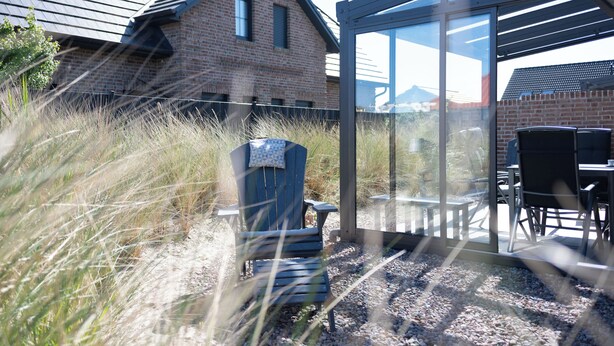 A house with a brick exterior, a glass door, and a patio area with outdoor furniture. - Modern vacation home directly on the Wangermeer. Comfort and maritime flair for families, couples and dog owners. (Wangerland)