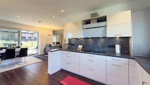 A modern kitchen with white cabinetry, a black countertop, and a red rug. - Modern vacation home directly on the Wangermeer. Comfort and maritime flair for families, couples and dog owners. (Wangerland)
