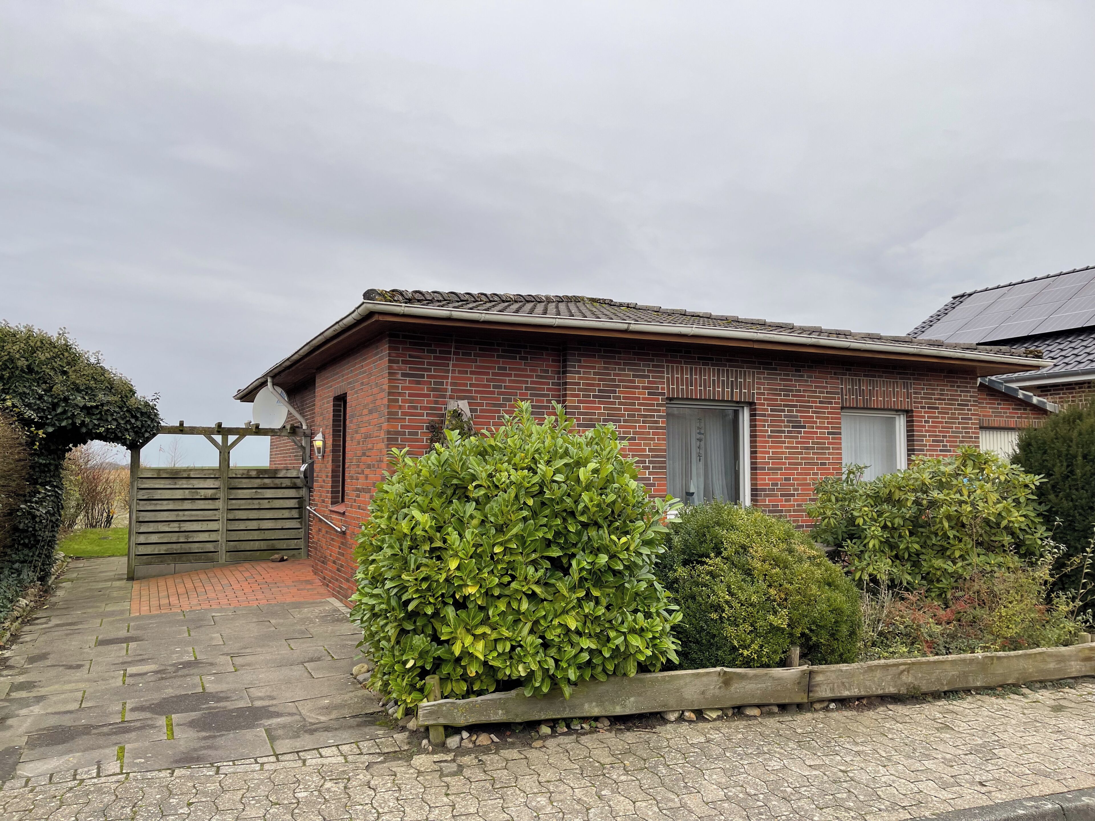 A brick building with a gated entrance, a small garden, and a paved pathway.