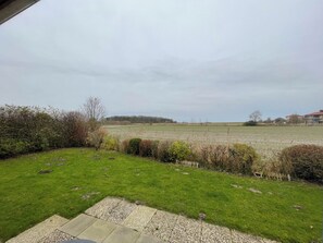 Eine Rasenfläche mit einem gepflasterten Weg, einem Feld und Gebäuden in der Ferne.