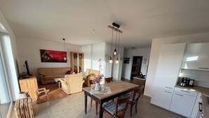 Een moderne woonkamer met een bank, eettafel en keukenhoek.