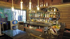 A bar area with a wooden interior, bar counter, hanging light fixtures, and shelves stocked with liquor bottles. - Oscar Boutique Hotel (Antalya)