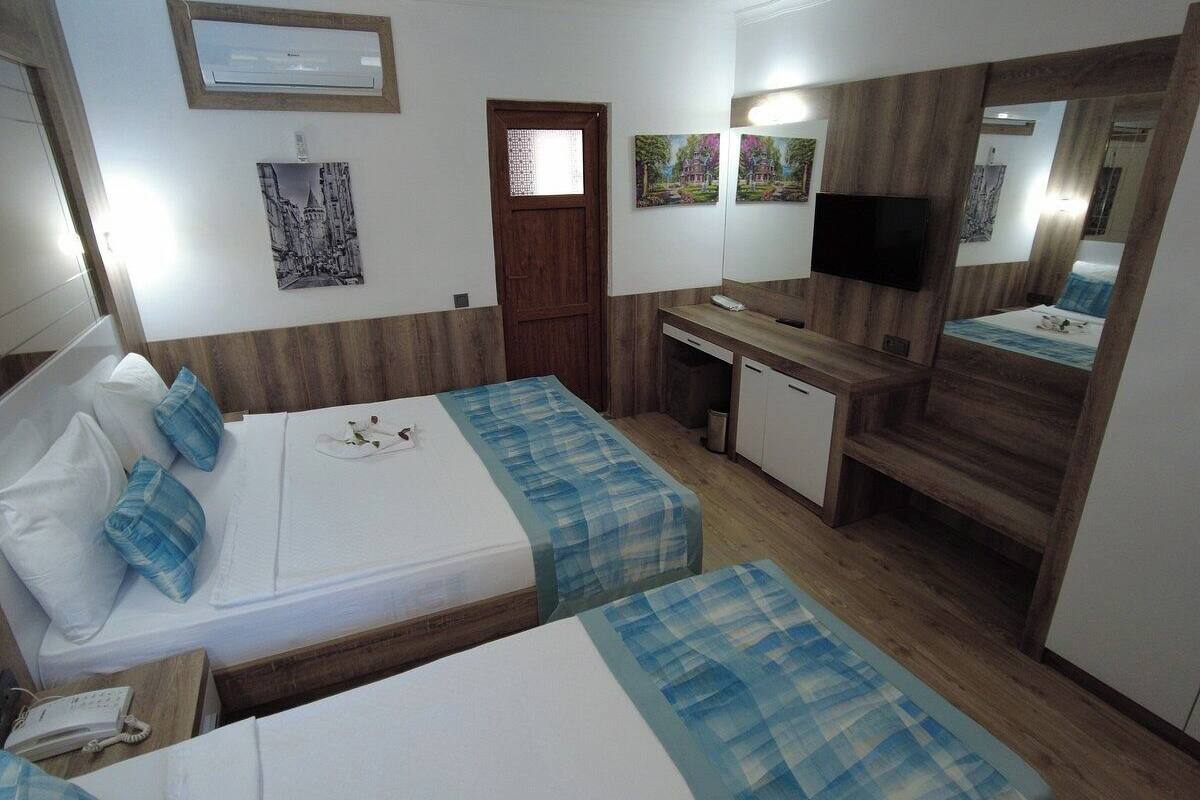 A hotel room with two beds, a desk, a mirror, and a TV.